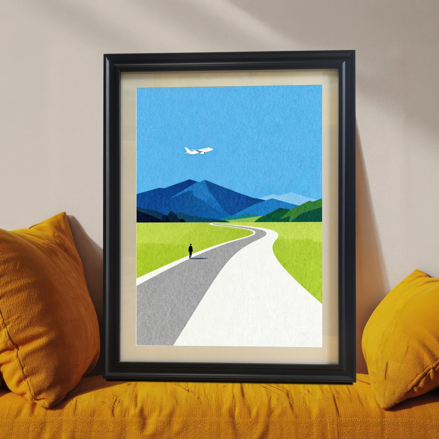 A black wood framed minimalist landscape art print with a cream mat mount, leaning on a bright mustard yellow sofa, showcasing a bold and modern home decor style.