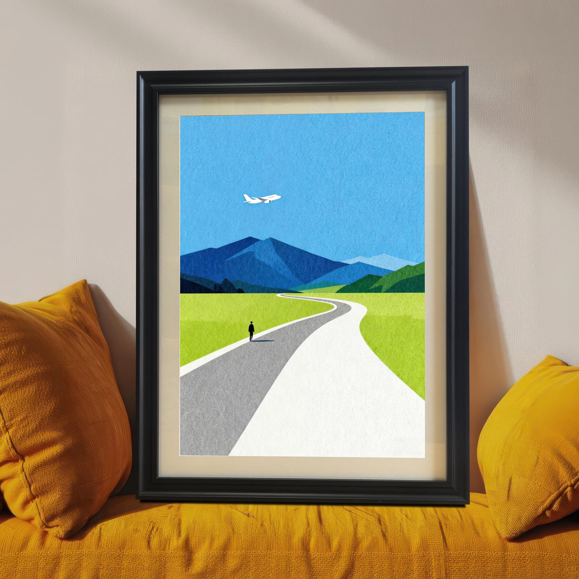 A black wood framed minimalist landscape art print with a cream mat mount, leaning on a bright mustard yellow sofa, showcasing a bold and modern home decor style.