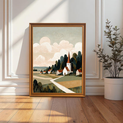 A wood-framed landscape art print of a village and church leaning against a white wall with elegant molding on a hardwood floor.