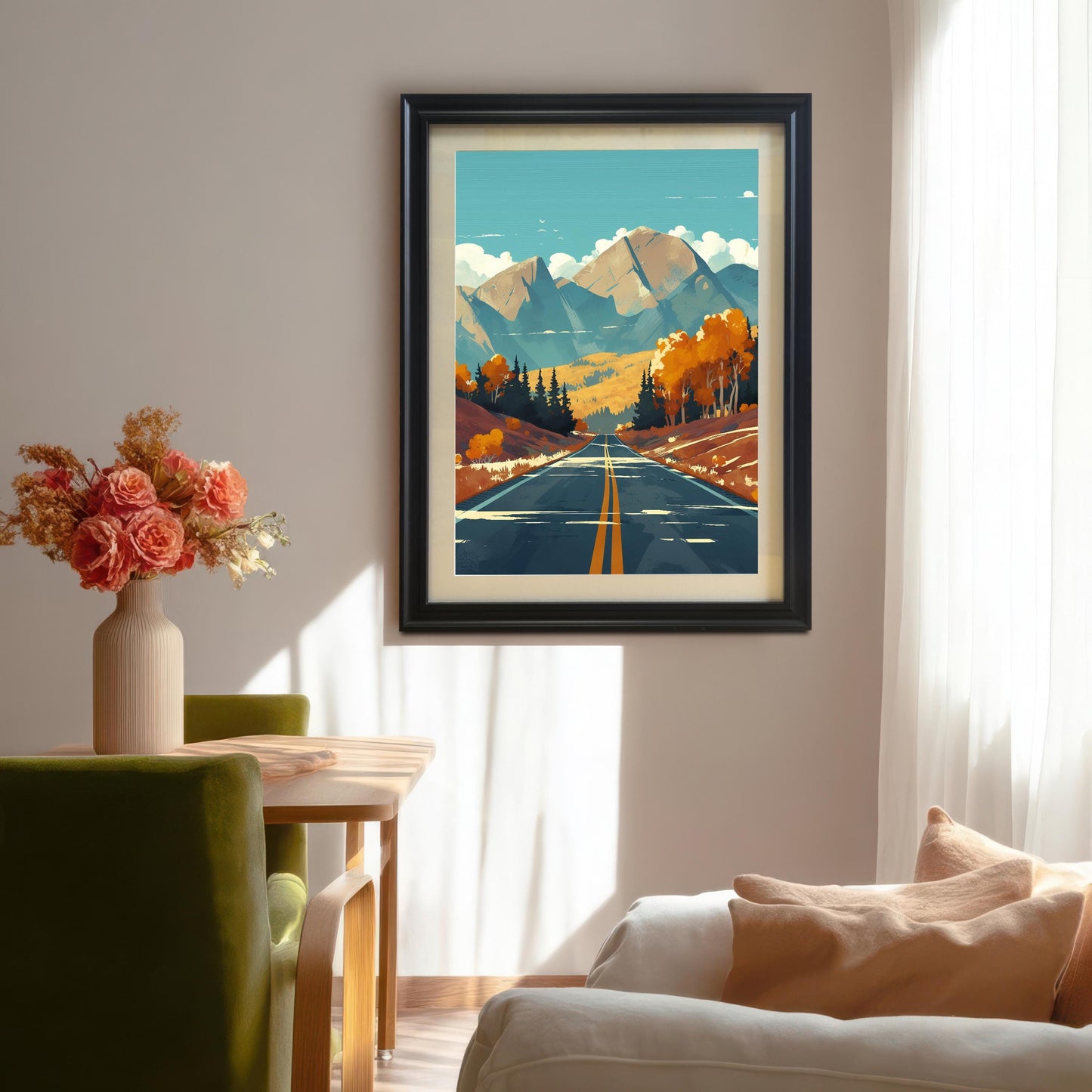 Large black wood framed autumn landscape art print with a white mount, hanging on a neutral wall in a sunny dining room above a wooden table with flowers.