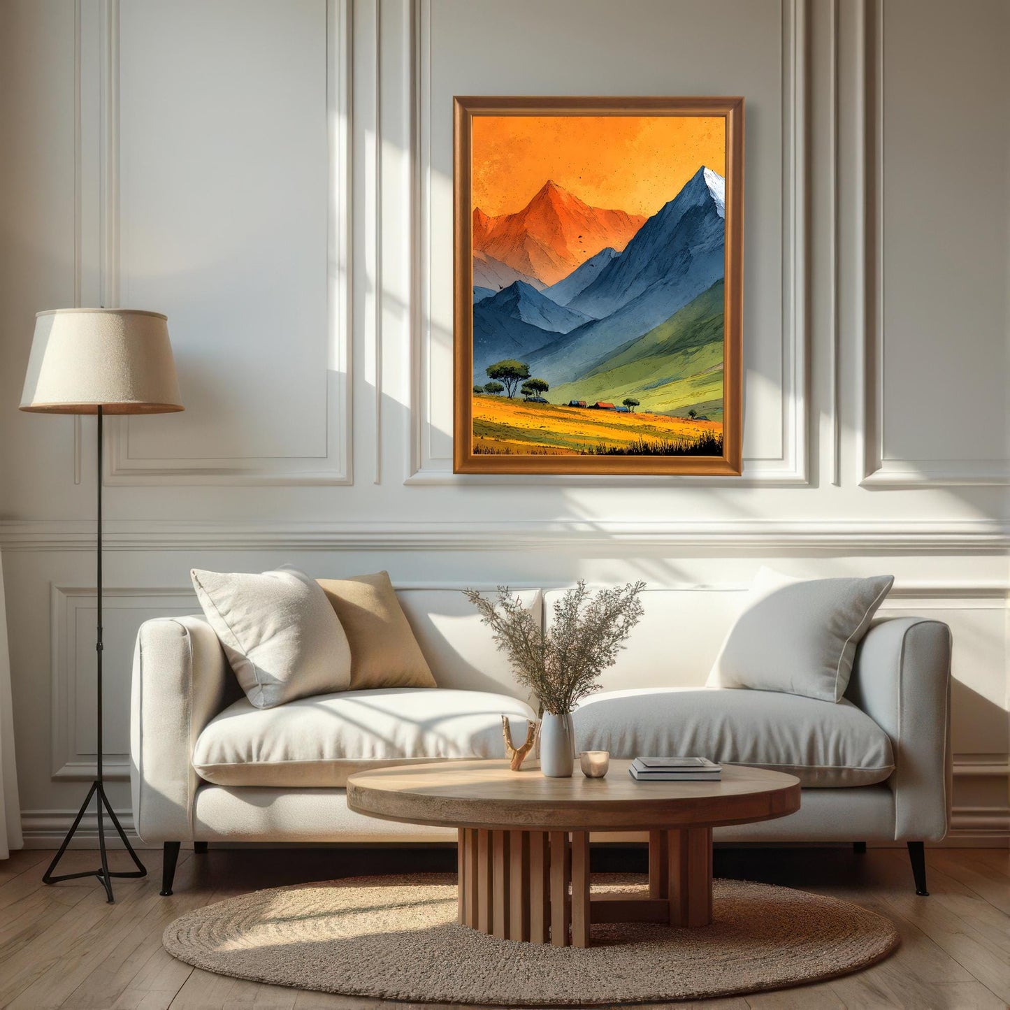 A large, orange-framed mountain landscape print hung centrally on a white paneled wall above a modern white sofa and a round wooden coffee table in a bright, sunlit room.