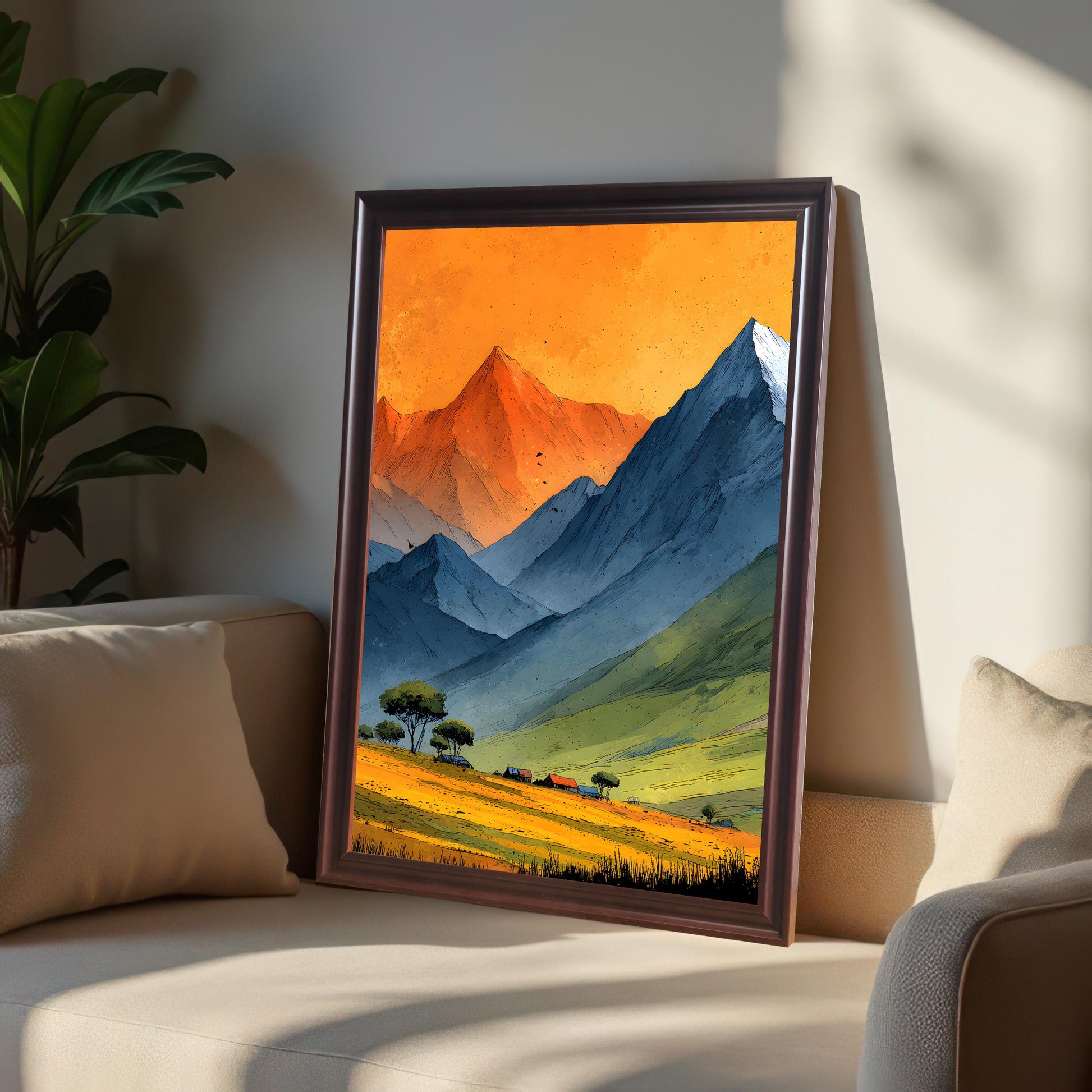 A coffee-colored wood frame featuring the mountain landscape print leaning against a sofa cushion. The warm lighting highlights the orange sky of the artwork and the texture of the frame.