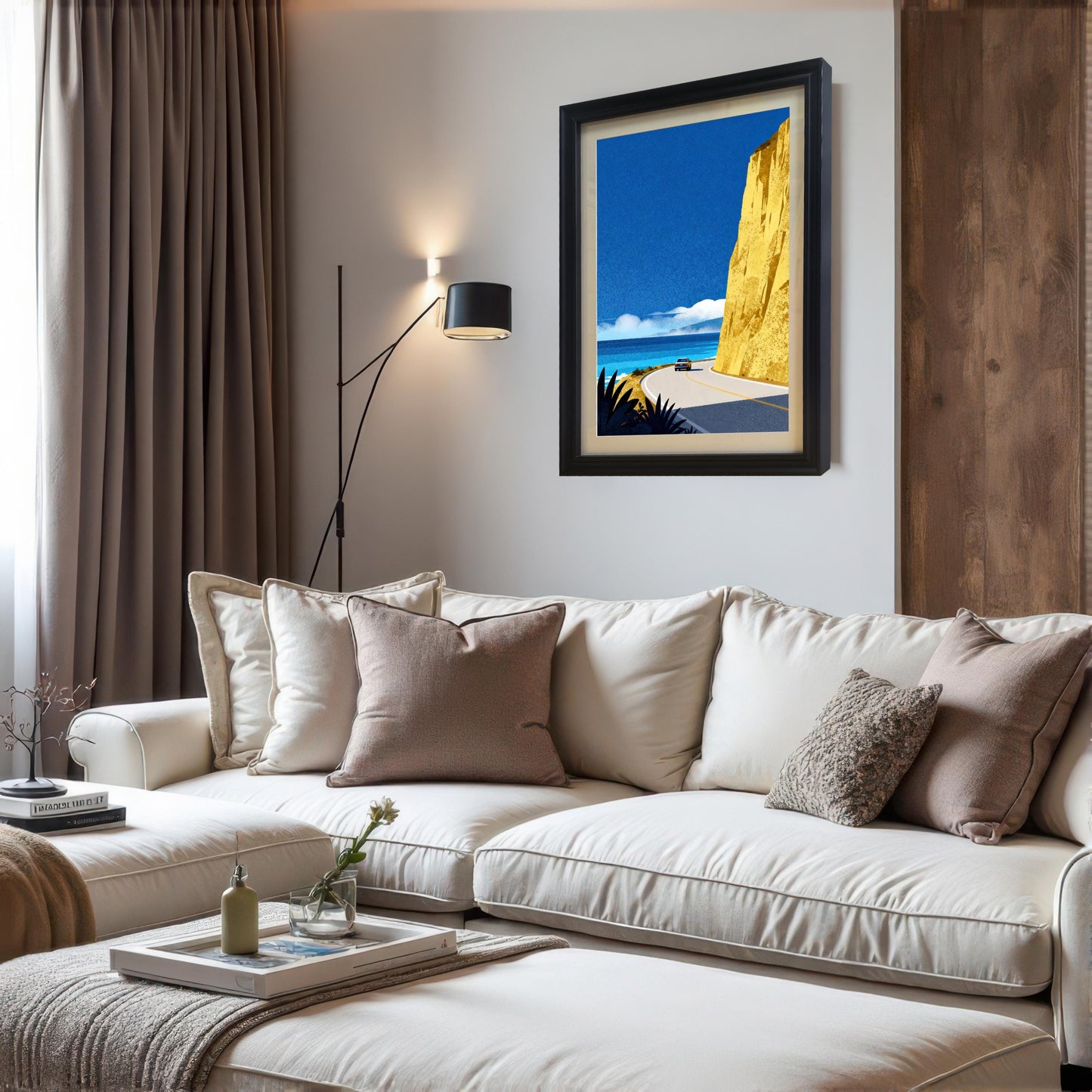 A black wood-framed art print with a cream mat board hanging on a white wall in a modern living room, styled above a white sectional sofa with neutral-toned pillows.