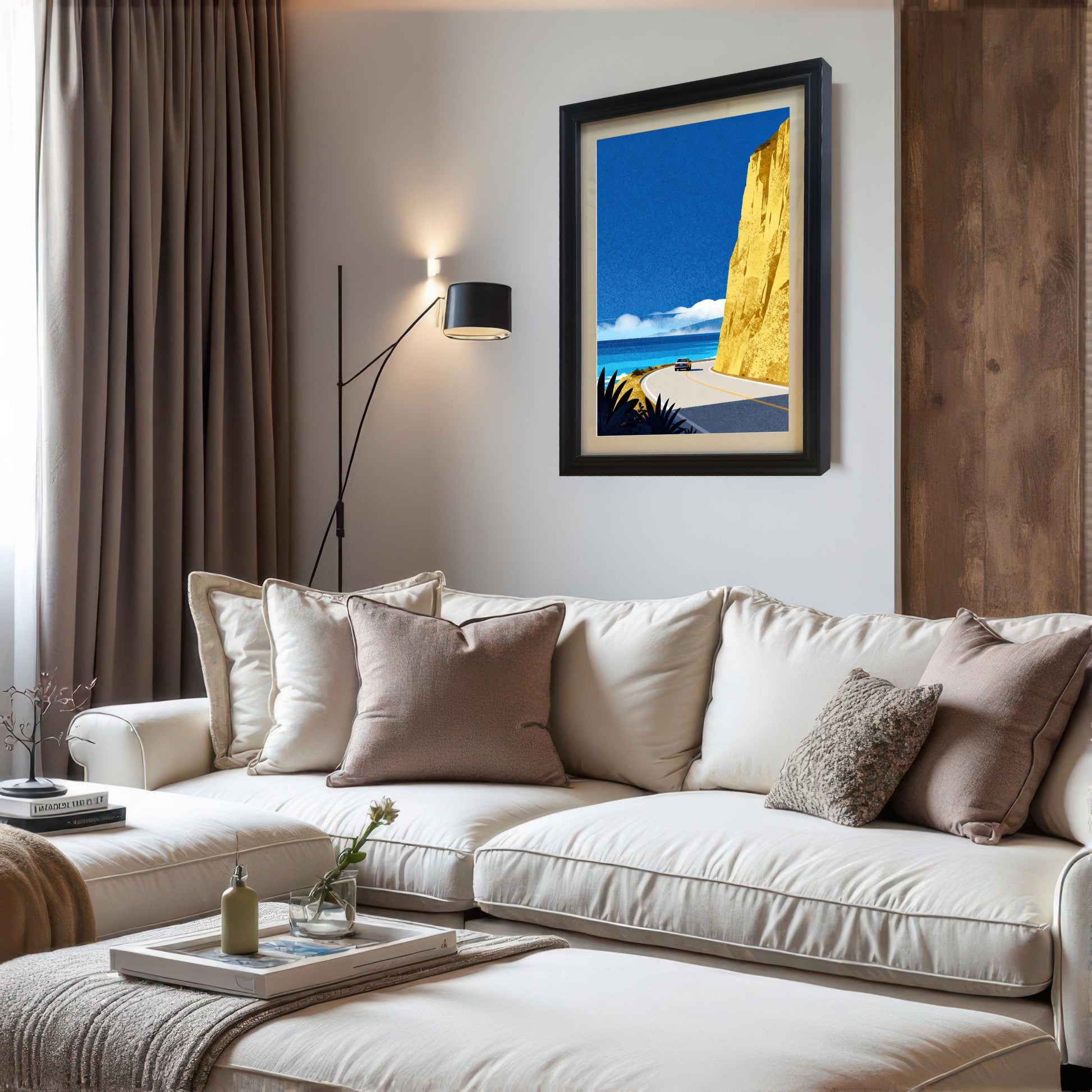 A black wood-framed art print with a cream mat board hanging on a white wall in a modern living room, styled above a white sectional sofa with neutral-toned pillows.