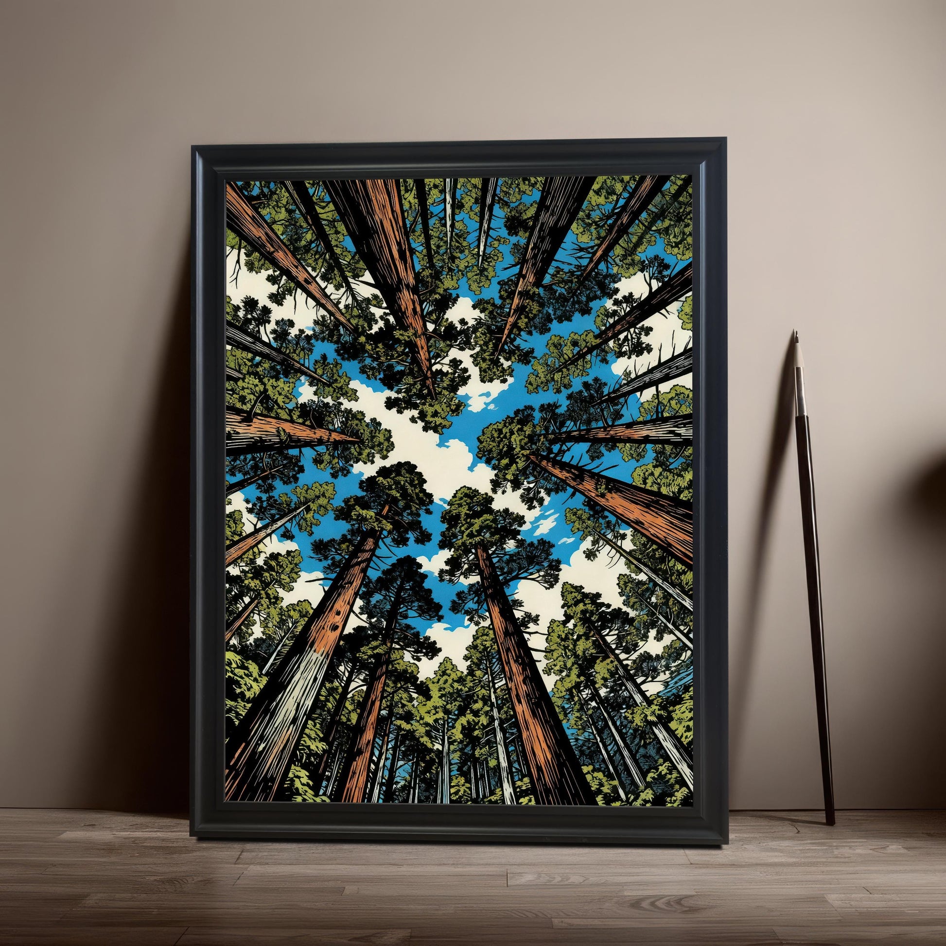 Vertical black wood framed wall art featuring a towering sequoia forest illustration from a worm's-eye view against a blue sky, leaning against a neutral wall.