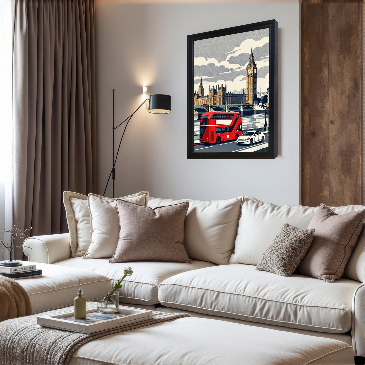 A black wood-framed art print of a London city scene mounted on a white wall above a modern white sectional sofa with neutral-toned throw pillows.