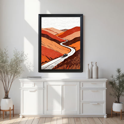 Large black-framed landscape art print of a winding mountain road centered on a white wall above a modern white sideboard cabinet with decorative vases and plants.