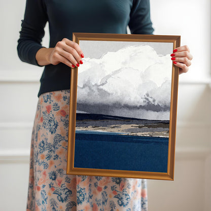A person holding the medium-sized abstract landscape print in an orange wood frame to demonstrate the physical scale of the product.
