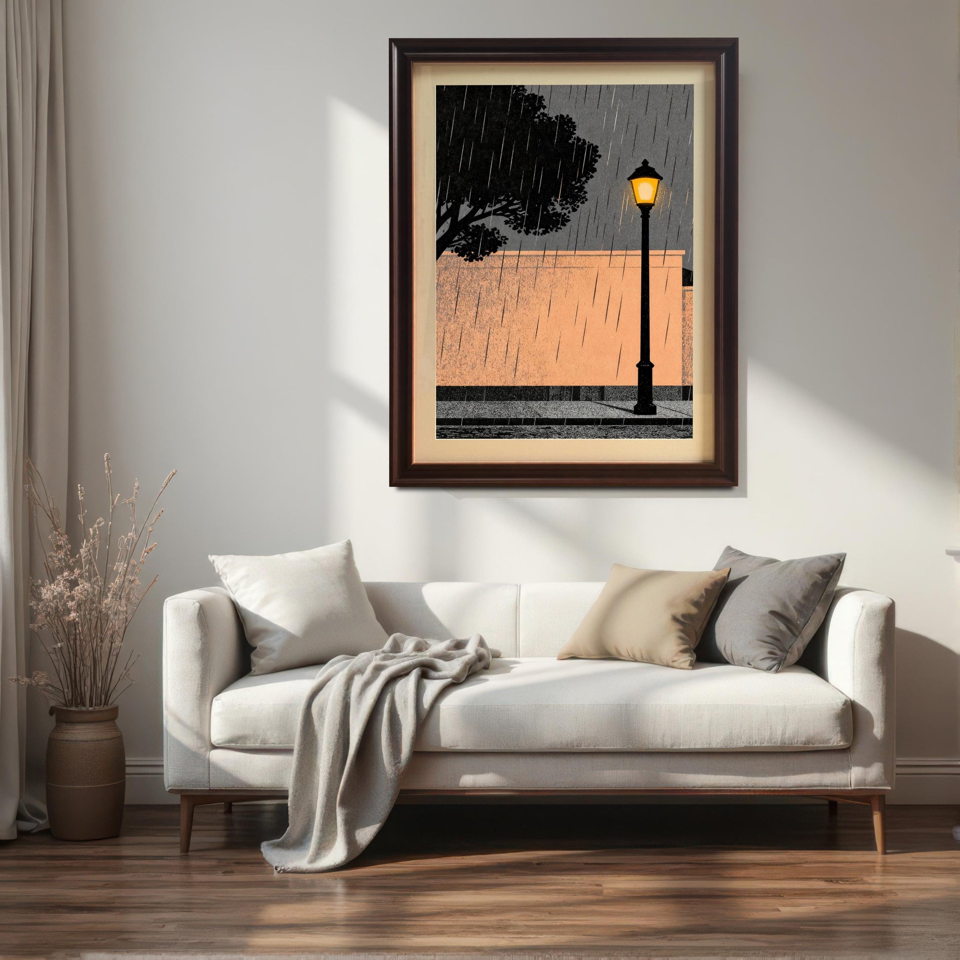 A large coffee-colored wood-framed art print with a white mount hanging on a bright, minimalist wall above a cream sofa with throw pillows and a decorative vase in a sunlit living room.