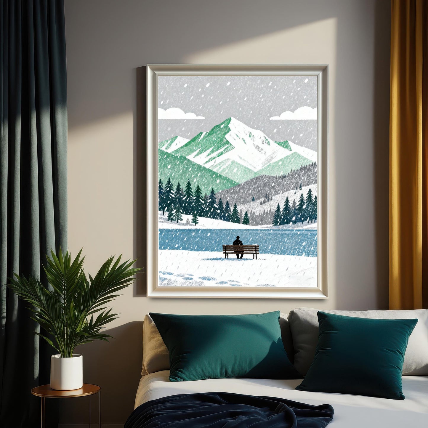 A framed art print in a white wood frame, hanging above a bed with teal pillows and a dark blue blanket. The artwork shows a winter scene with green mountains, a lake, and a lone person on a bench. Green and yellow curtains frame the print.