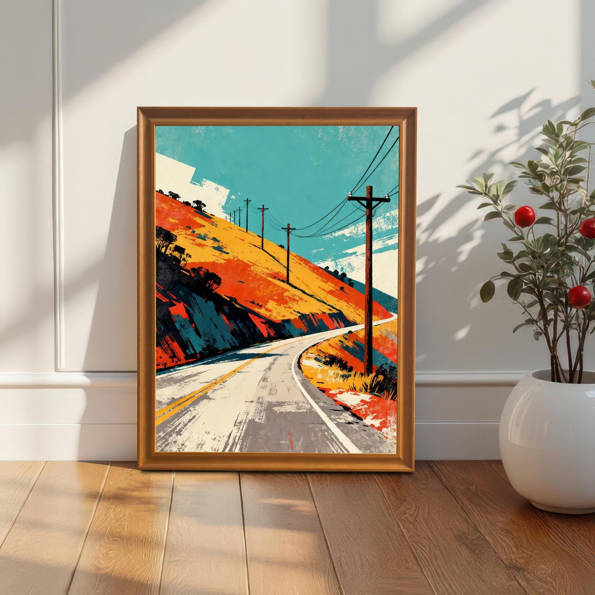 Framed art print in an Orange or light wood frame, leaning against a white wall next to a white planter with a small red-berried plant. Natural sunlight creates a dramatic diagonal shadow across the wall and print.