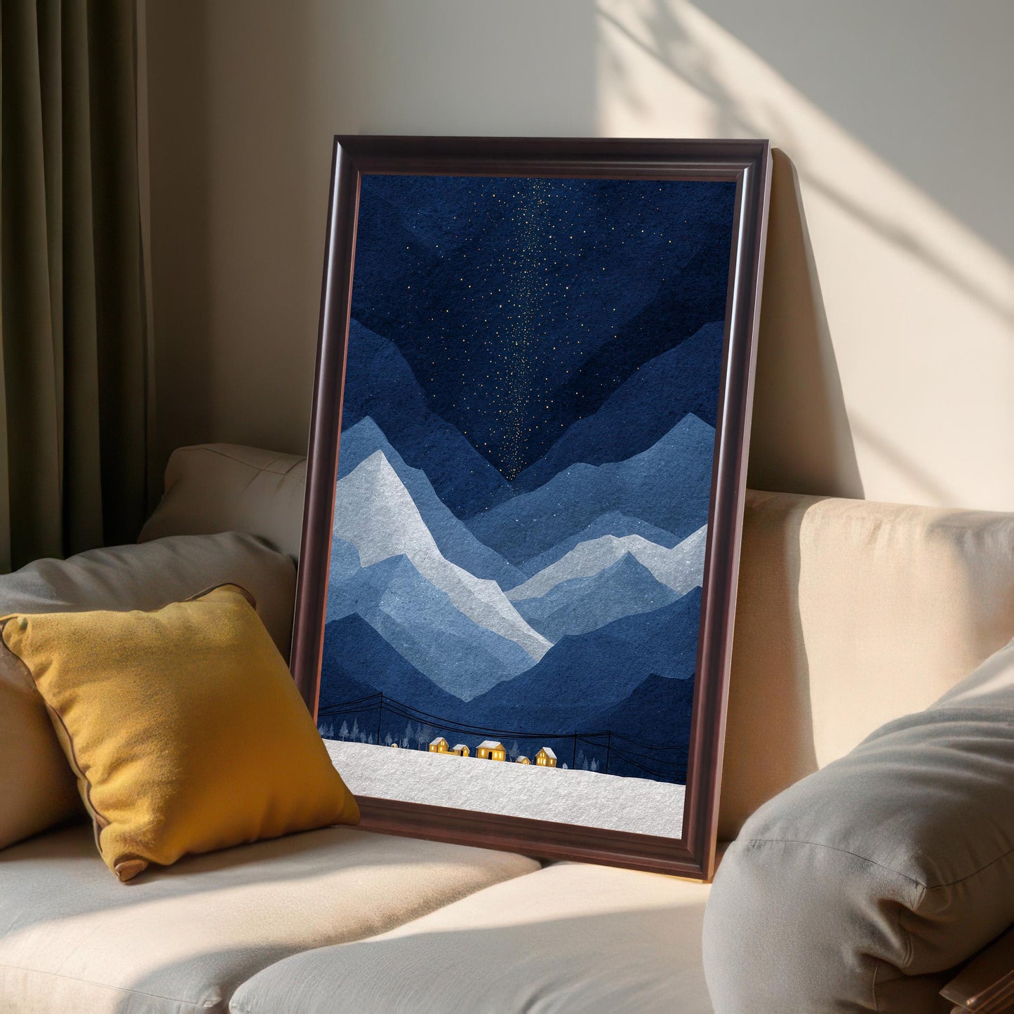 A dark wood-framed mountain art print leaning against a beige sofa in a sunlit room, showcasing the frame's texture and the print's deep blue colors.