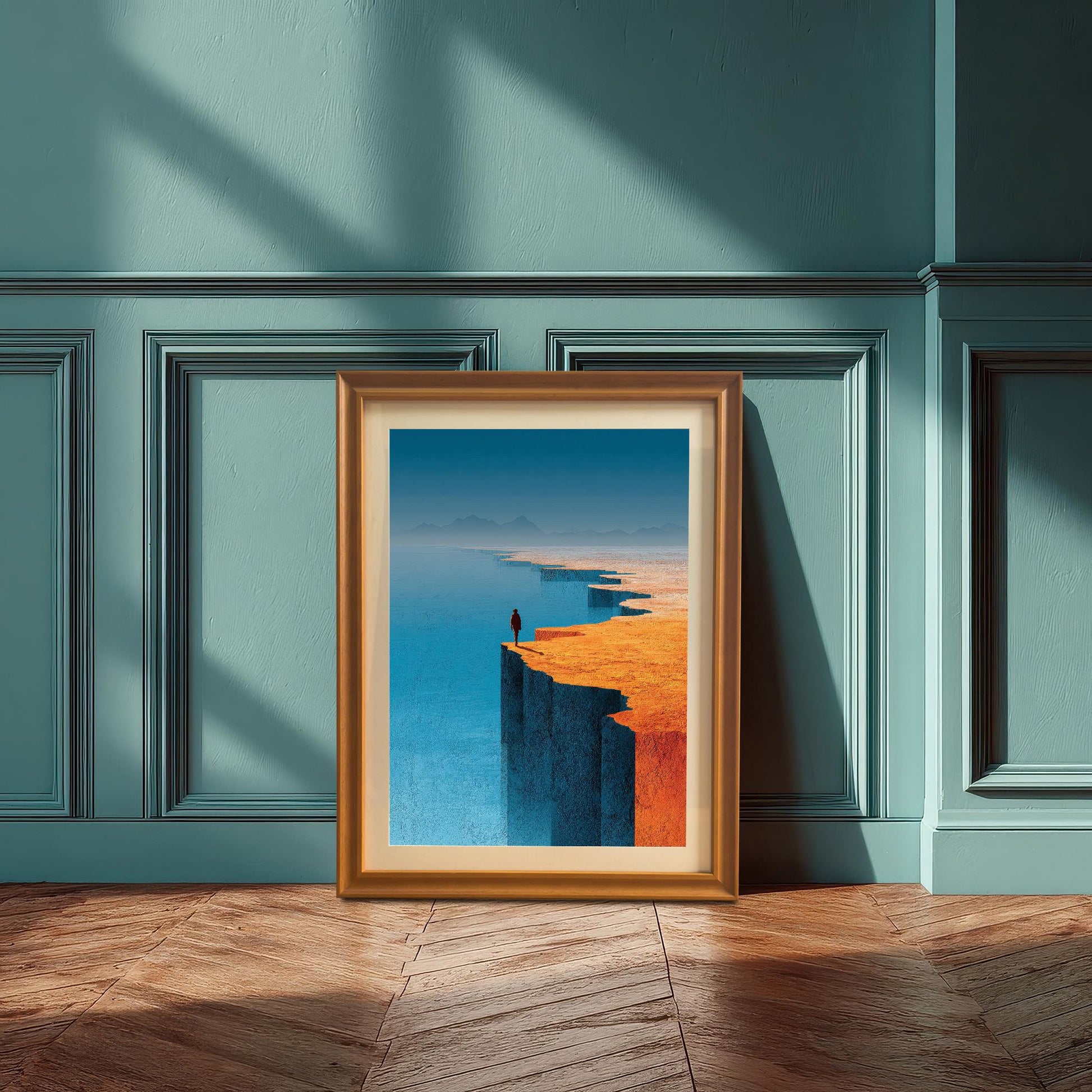 A minimalist landscape art print in an orange wood frame with a mat, leaning against a teal-blue wainscoted wall. The scene is illuminated by natural sunlight casting shadows across the wooden parquet floor.
