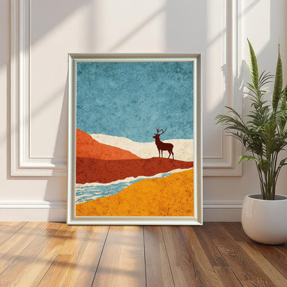 A large white-framed minimalist art print featuring a stag silhouette in a landscape of teal, orange, and gold, leaning against a white paneled wall next to a potted plant.