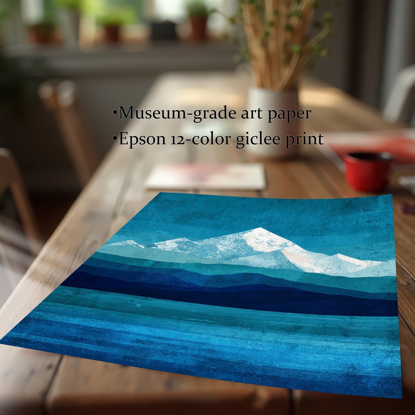 Close-up detail of the unframed mountain art print resting on a wooden table. Text overlay highlights "Museum-grade art paper" and "Epson 12-color giclee print," emphasizing the high-quality texture and rich blue pigments.