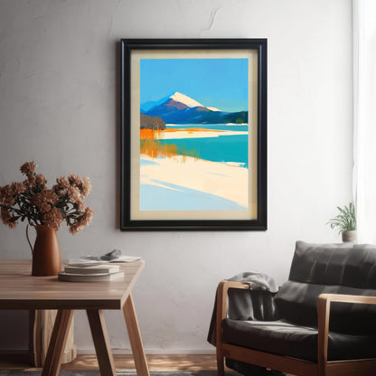 A black-framed mountain landscape art print hanging on a textured white wall in a modern living space. The scene includes a wooden desk with books and a vase of flowers in the foreground, and a stylish armchair to the right.