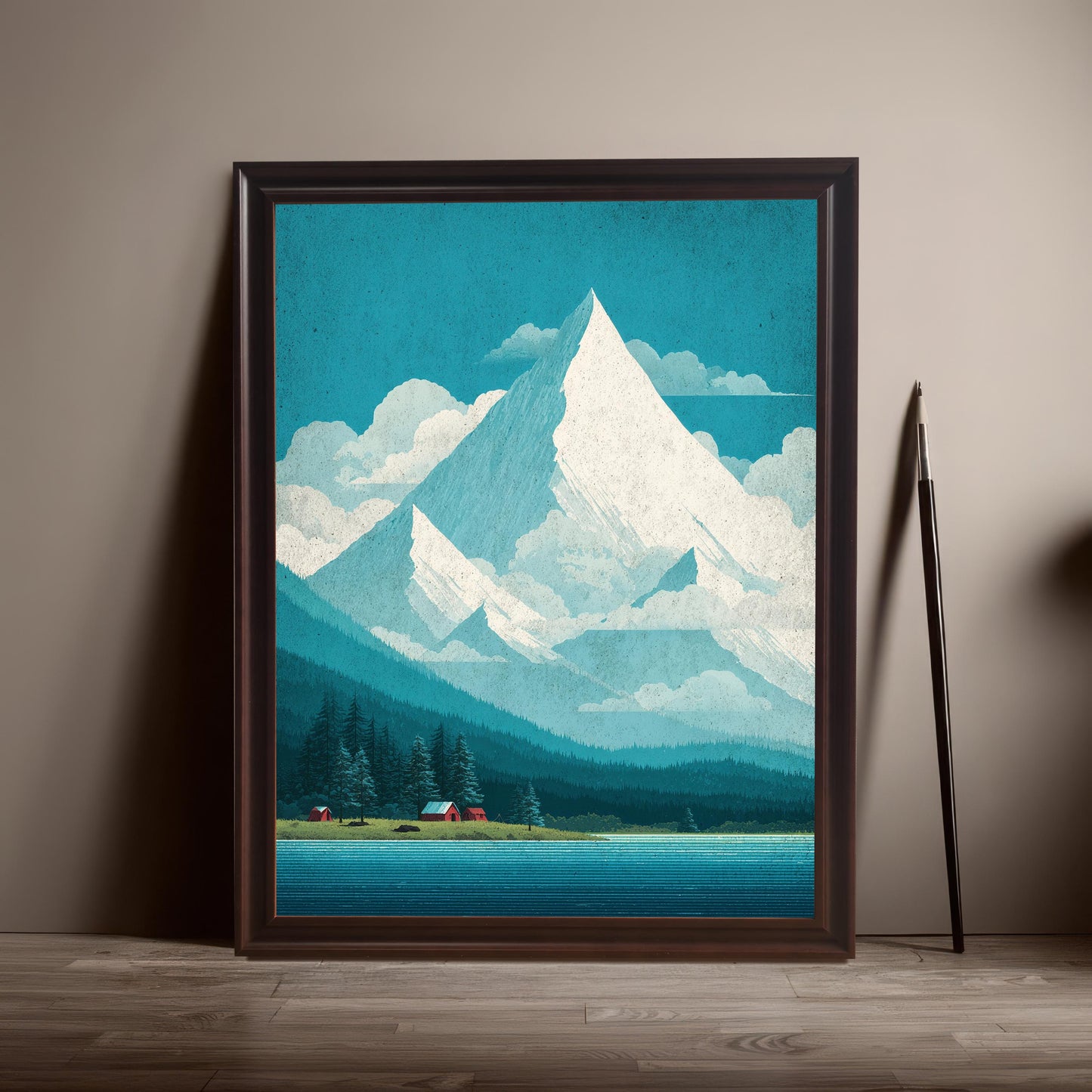 A coffee-colored wood frame featuring the teal mountain landscape print leaning against a neutral-toned wall on a dark wood floor, styled with a tall artist's paintbrush.