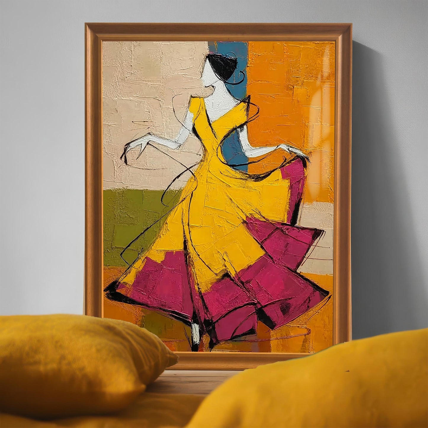 A large framed print of the yellow-dressed dancer sitting on the floor leaning against a grey wall, partially obscured by soft yellow pillows in the foreground for a cozy home decor feel.
