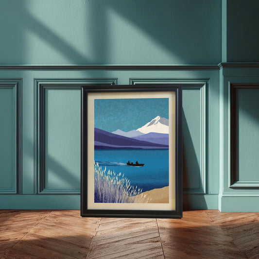 A vertical black wood framed art print featuring a serene mountain and lake landscape leaning against a teal wainscoted wall on a herringbone wood floor. The print includes a cream-colored mount.