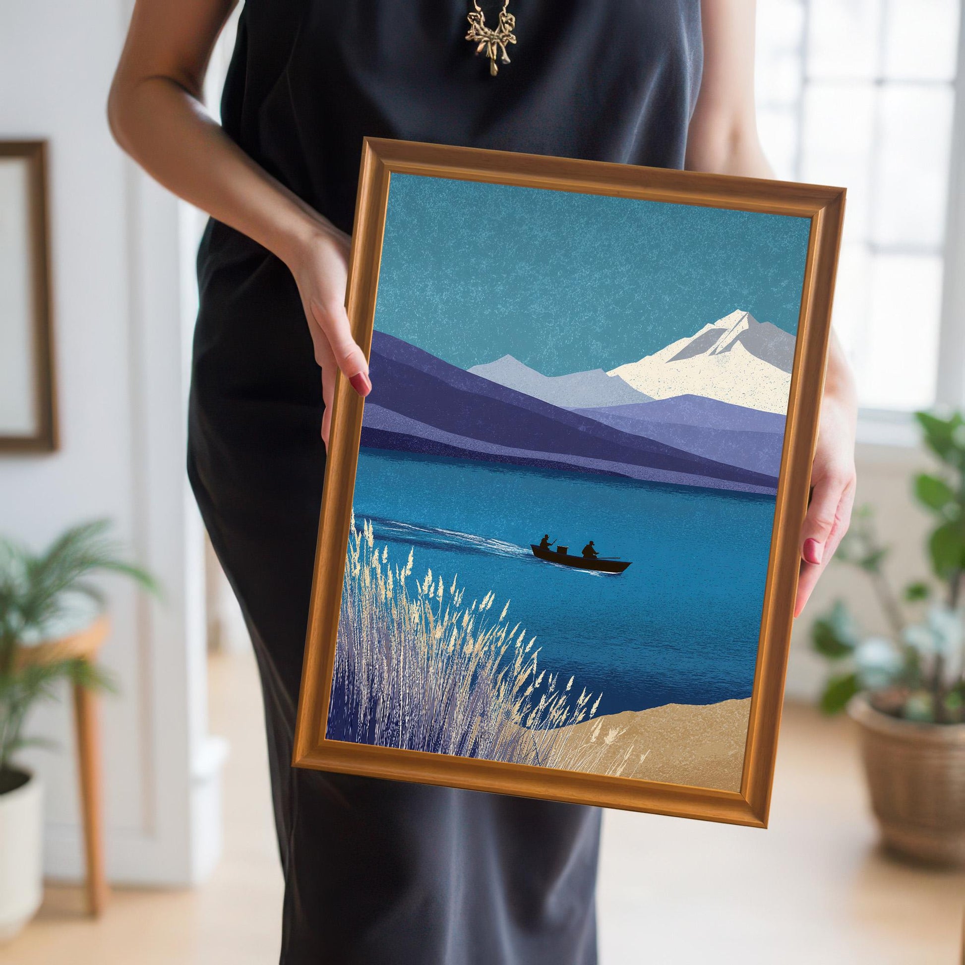 A person holding a medium-sized orange wood framed print of the mountain and lake scene, providing a real-life sense of scale and handling.