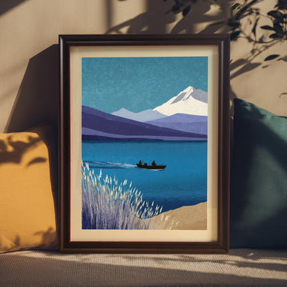 A coffee-colored wood framed art print with a cream mount, nestled between a yellow and a dark teal pillow on a textured surface. Soft sunlight and leaf shadows fall across the frame and the neutral wall behind it.