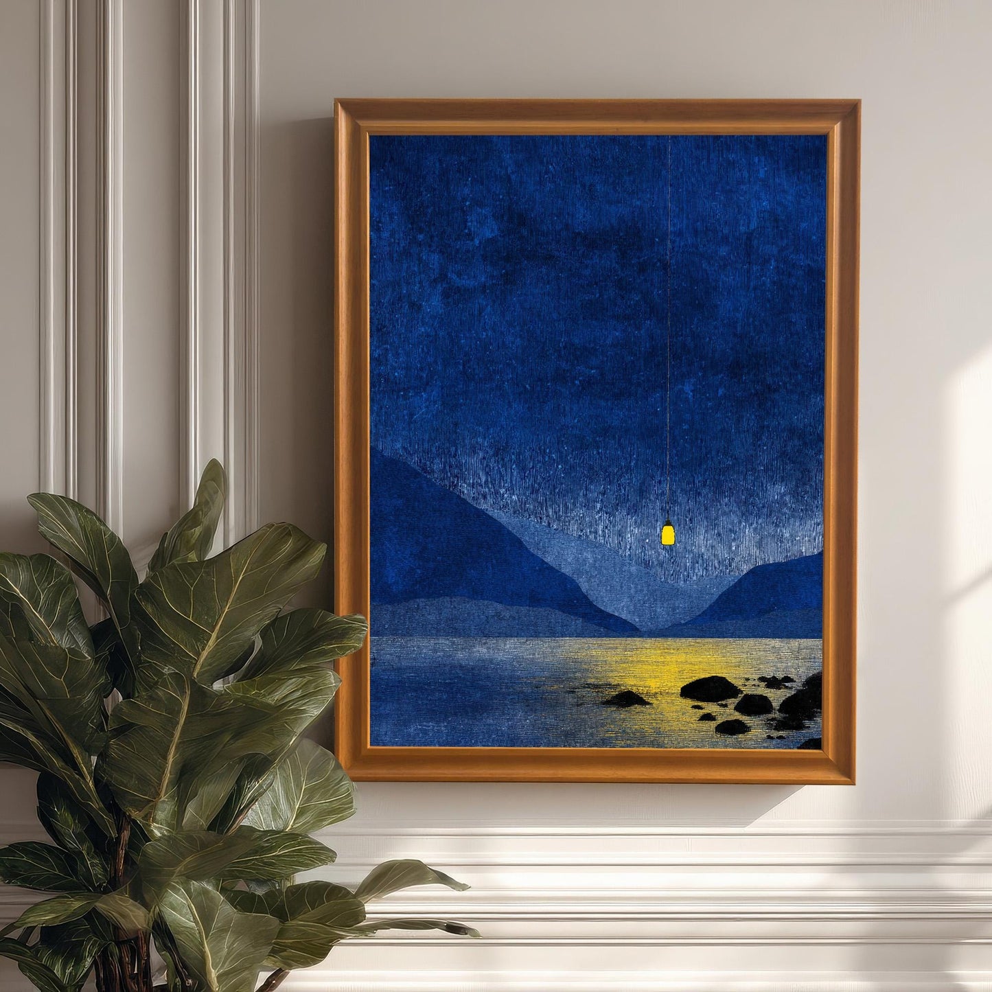 Orange wood framed blue landscape art hanging on a white paneled wall above a large green indoor plant.