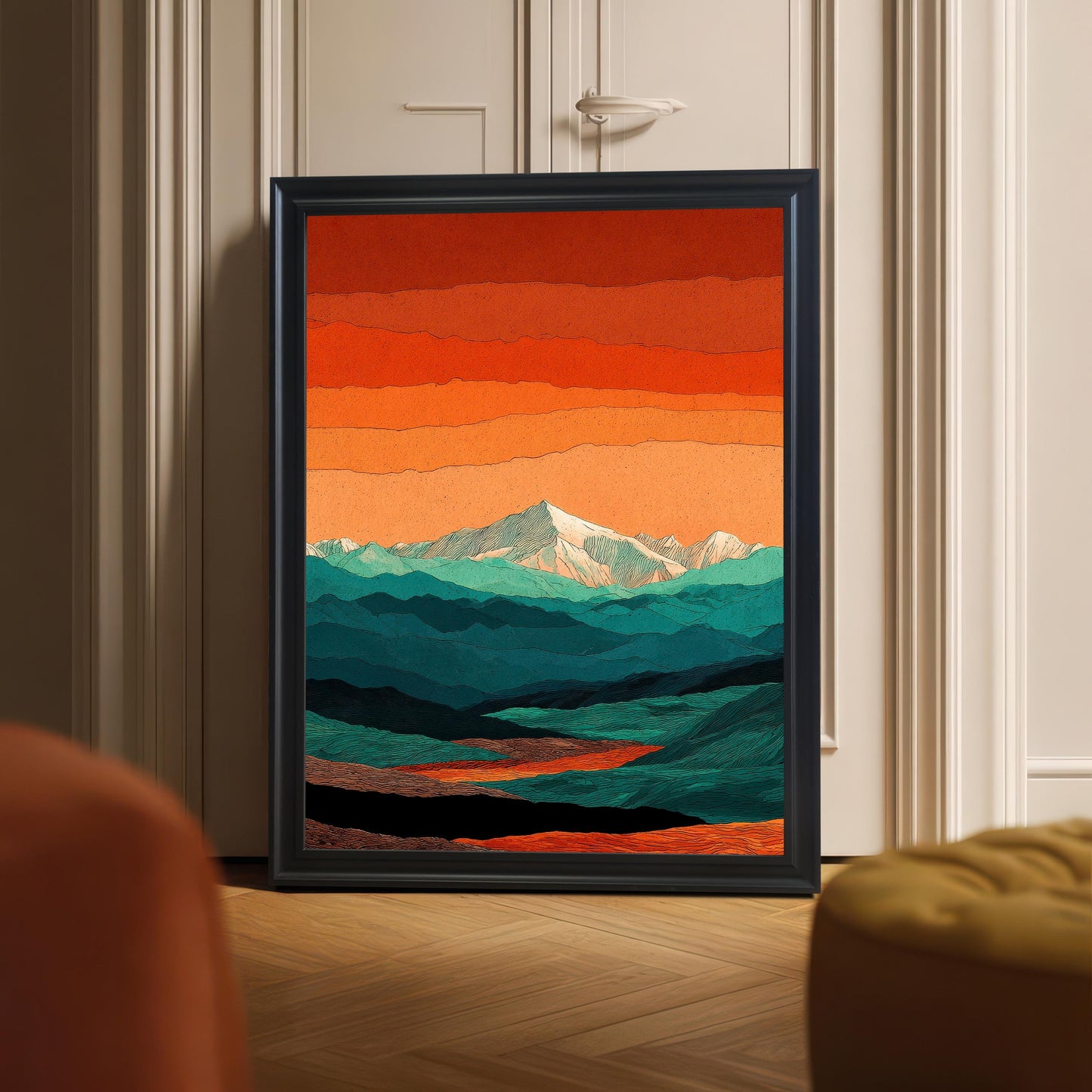 A black-framed mountain landscape art print leaning against a white paneled door on a light wood herringbone floor in a modern room.