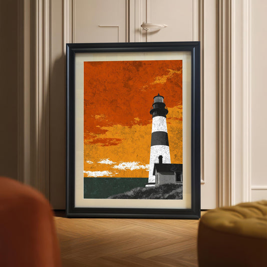 A large black wood-framed lighthouse art print with a white mount, leaning against a neutral wall on a herringbone wood floor in a modern room setting.