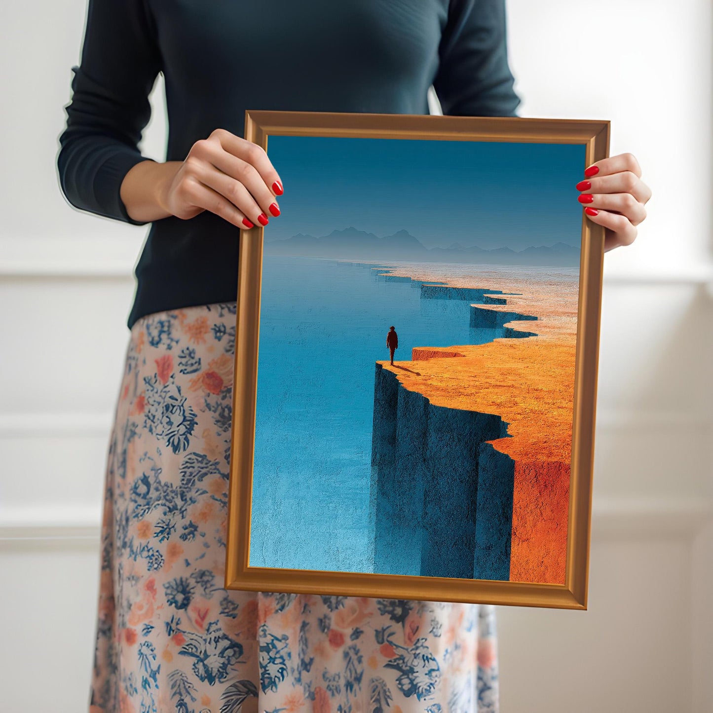 A person holding a medium-sized, orange-wood framed landscape art print in front of them to demonstrate the physical size and scale of the product.