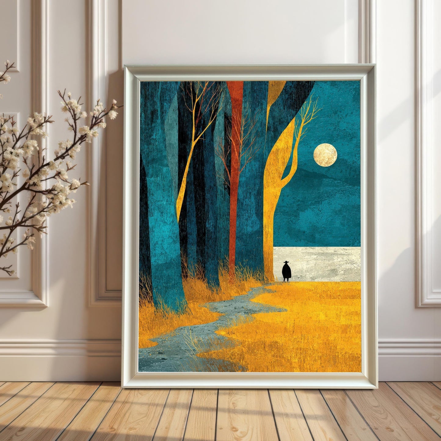 A large white-framed art print of the moonlit forest landscape leaning against a white paneled wall on a light wood floor, creating a bright and airy aesthetic.