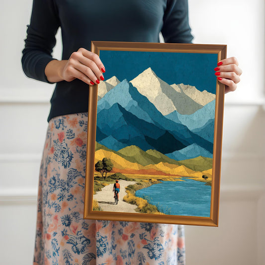 A person holding an orange wood-framed mountain landscape print to provide a real-world sense of size and frame quality.