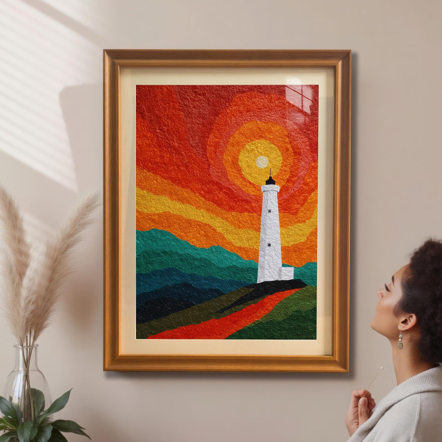 A woman looking at a large, orange-framed lighthouse art print hanging on a neutral wall next to pampas grass decor.