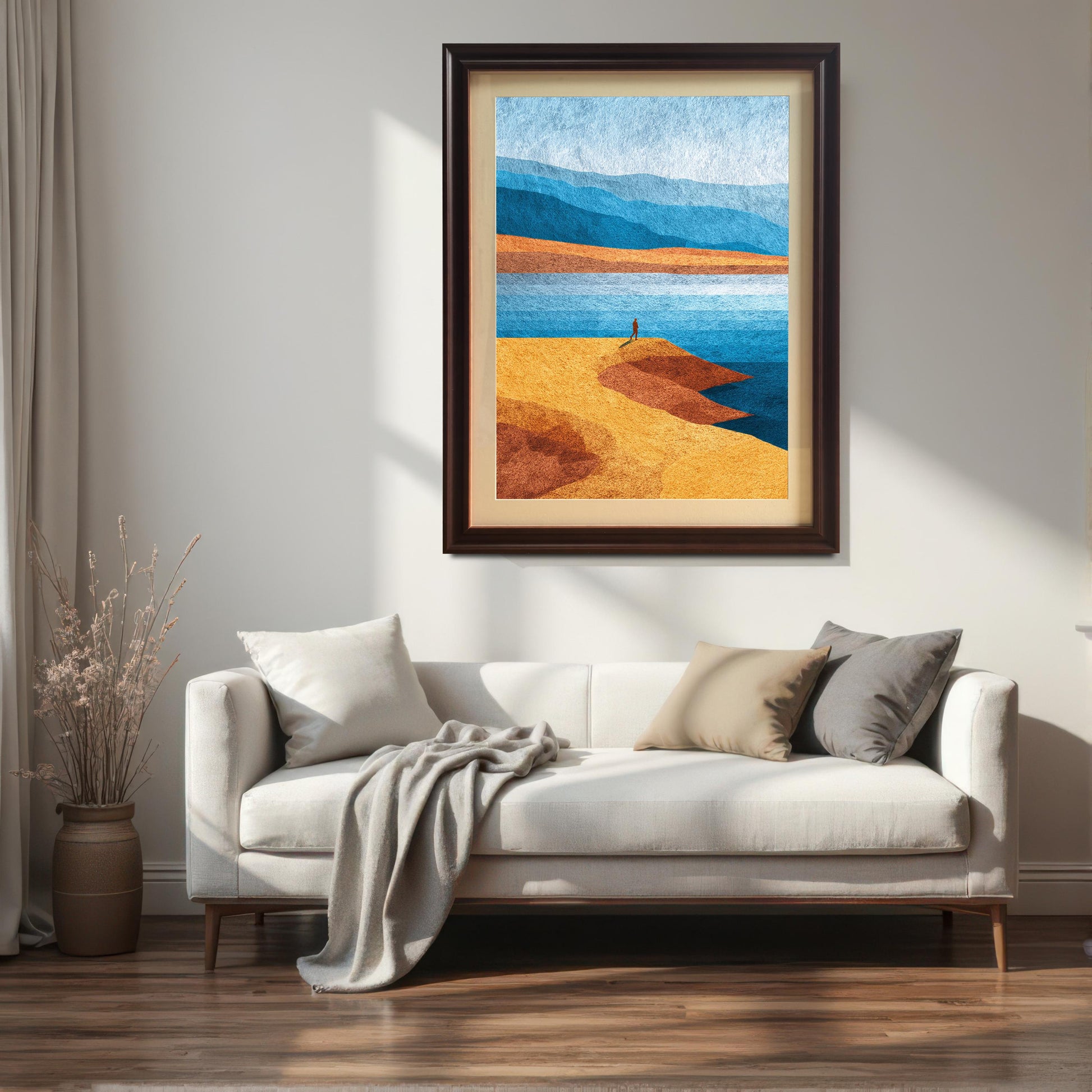 Modern dark coffee wood framed landscape art hanging above a cream sofa with neutral pillows and a soft grey throw, creating a cozy and sophisticated living room scene.