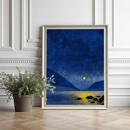 White wood framed blue mountain print leaning against a white decorative wall next to a potted plant on a herringbone wood floor.