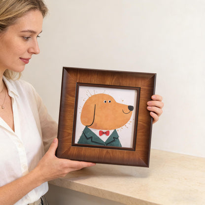 A woman holding a square dark wood picture frame featuring a naive art style illustration of a golden retriever-like dog in a tuxedo.