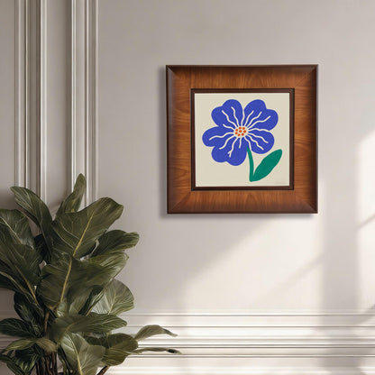 Square wood-framed blue flower wall art mounted on a cream-colored classic paneled wall next to a large indoor green plant.