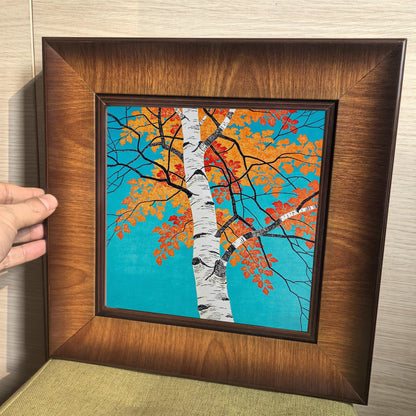 A hand holding the square framed art print against a neutral background, demonstrating the sturdy build and the premium finish of the solid wood frame.