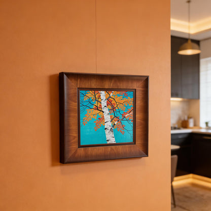 Close-up of a wide wood picture frame featuring a vibrant birch tree illustration with orange autumn leaves on a teal background.