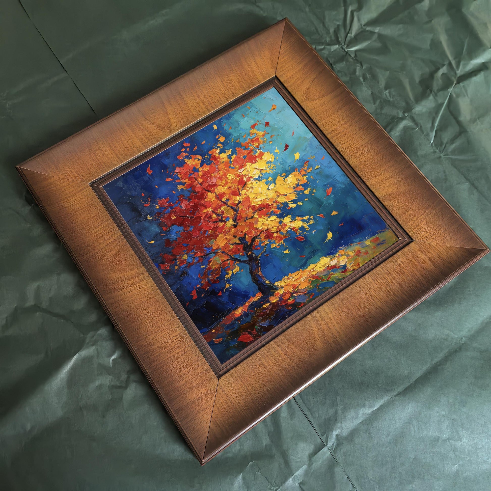 High-angle shot of a square walnut-finish framed print featuring an abstract impasto painting of a colorful tree against a dark teal background.