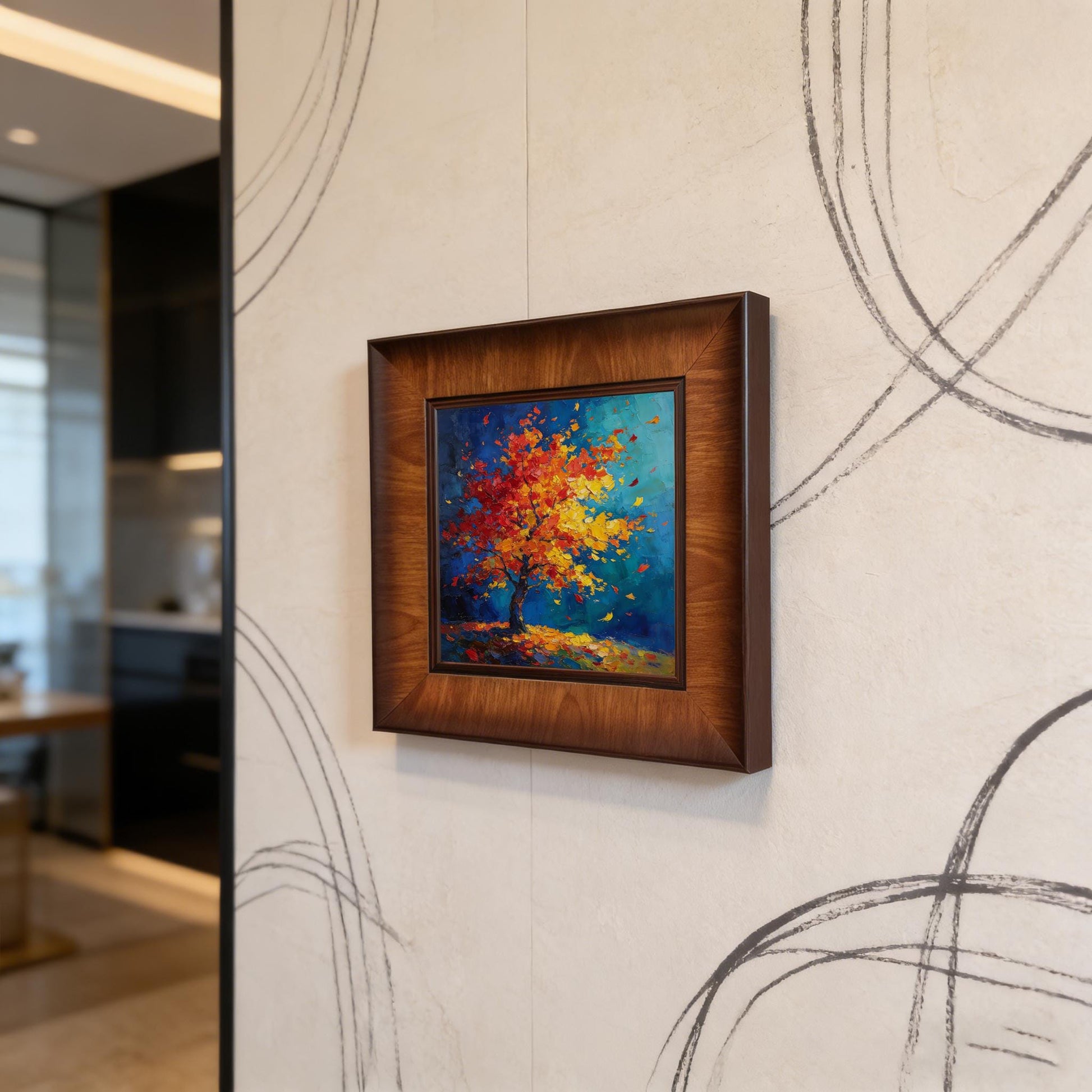 A square wood-framed abstract painting of a colorful autumn tree with red and yellow leaves is mounted on a modern textured wall featuring dark geometric linear patterns.