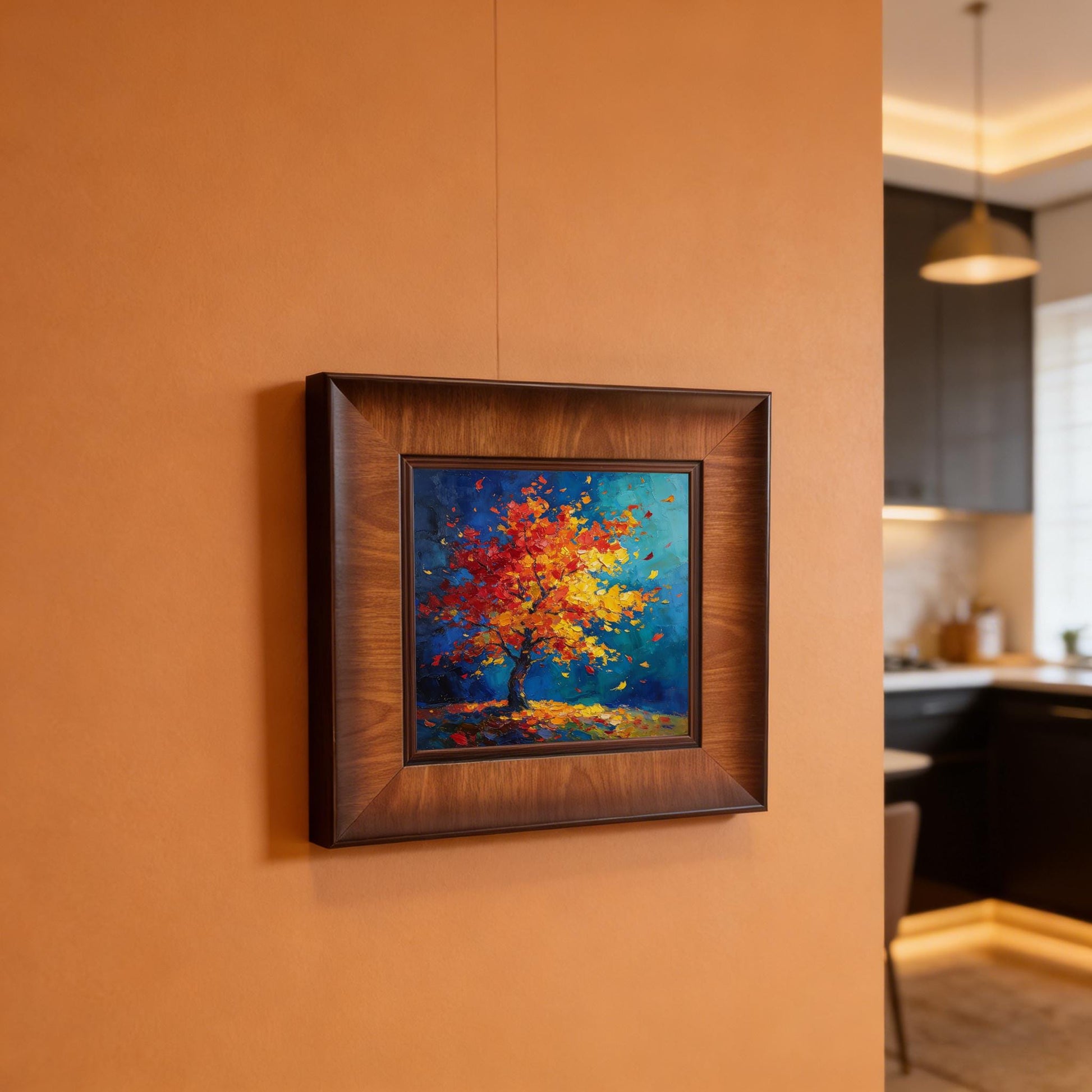 Square wood-framed impasto painting of a red tree mounted on a terracotta-colored wall in a modern interior setting.