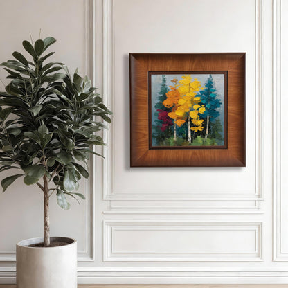 Square walnut-framed landscape art hanging on a white paneled wall next to a tall fiddle leaf fig plant in a white pot.