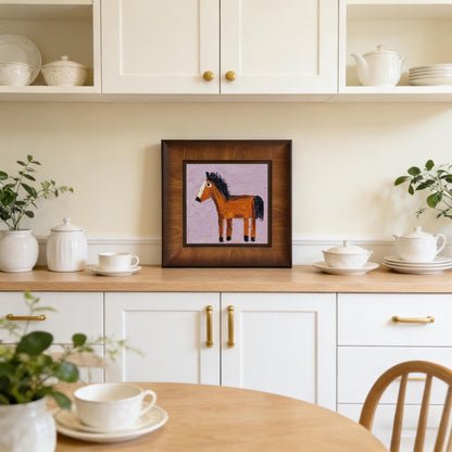 Textured horse art print in a dark wood frame displayed on a kitchen counter, showing its versatility as home decor in a bright, white kitchen.