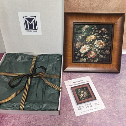 An unboxing display of the "Secret Garden" art piece. The framed print sits next to its "Miracle Walls" gift box, which is lined with dark green tissue paper and tied with a gold-and-black striped ribbon. The product info card is featured in the foreground.