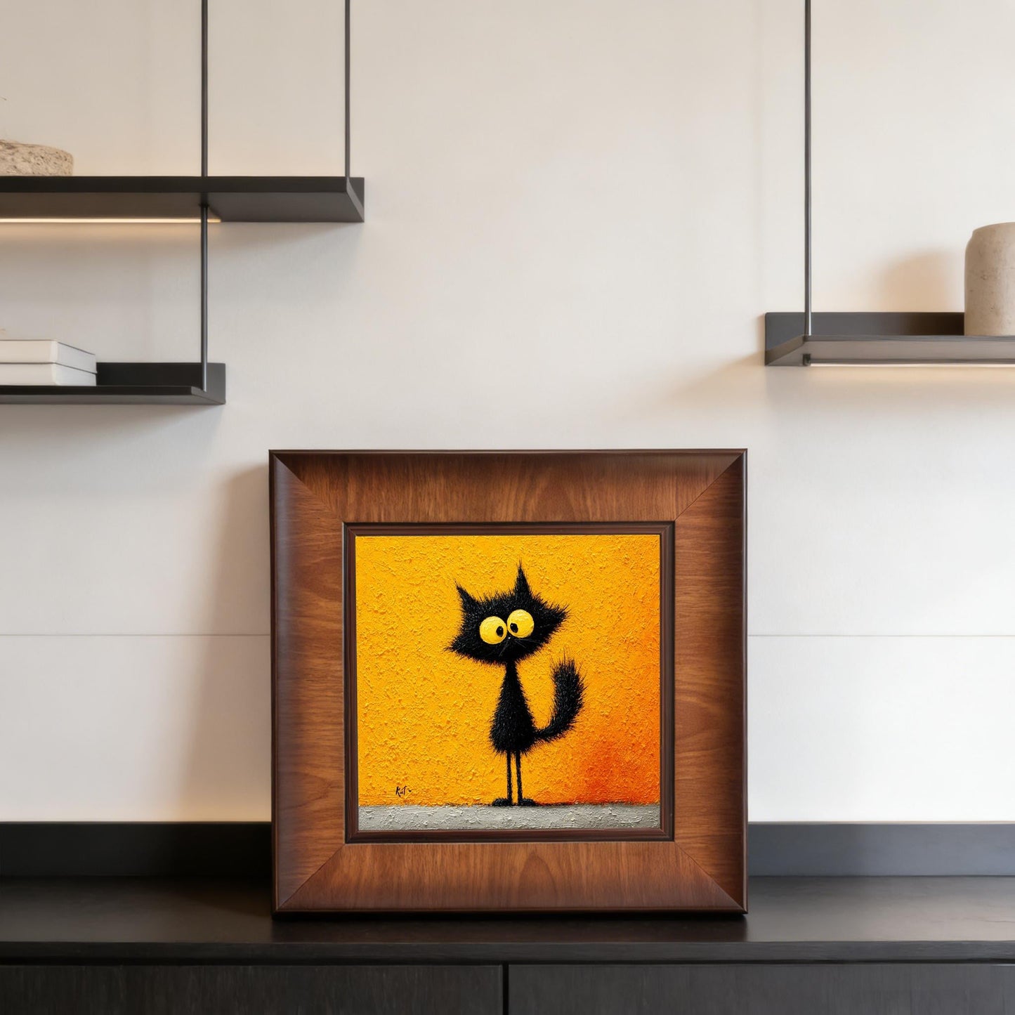 Square framed black cat painting displayed on a black sideboard in a contemporary interior with minimalist floating shelves.