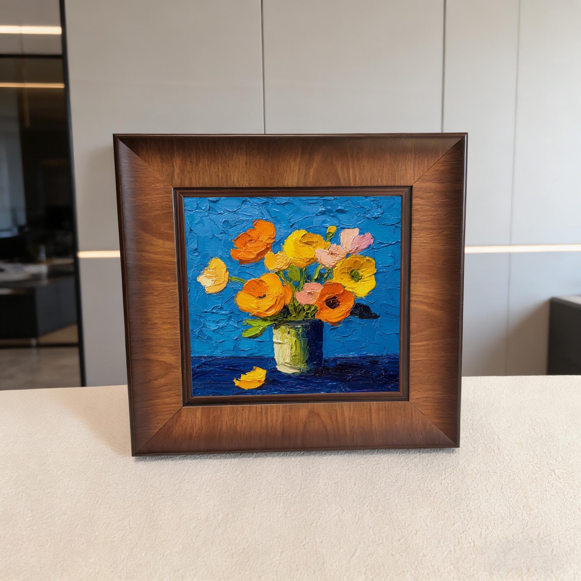 Square wood-framed textured flower painting displayed on a white console table in a minimalist, high-end room setting.