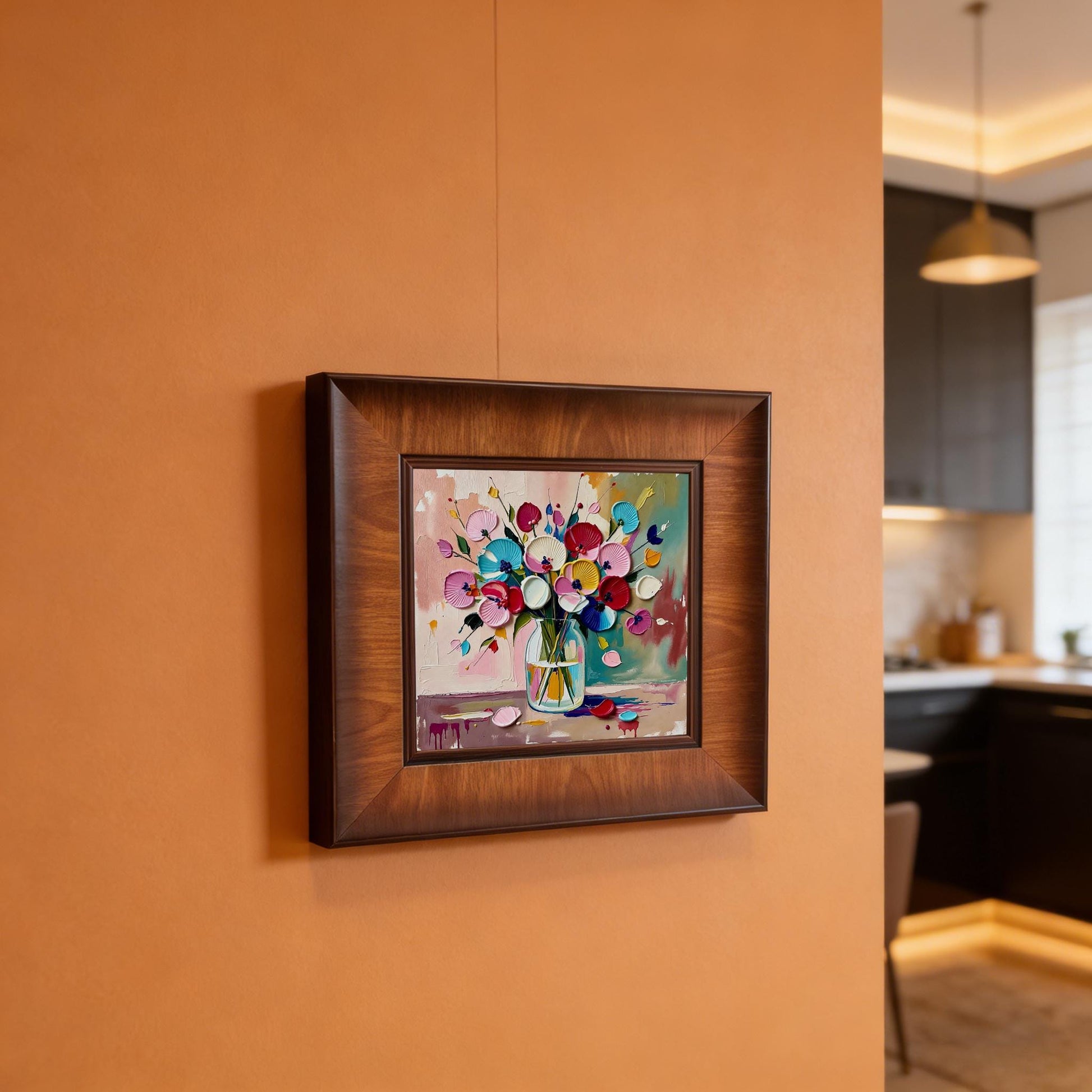 Square floral impasto print in a dark wood frame hanging on a warm terracotta-colored wall in a modern kitchen setting.