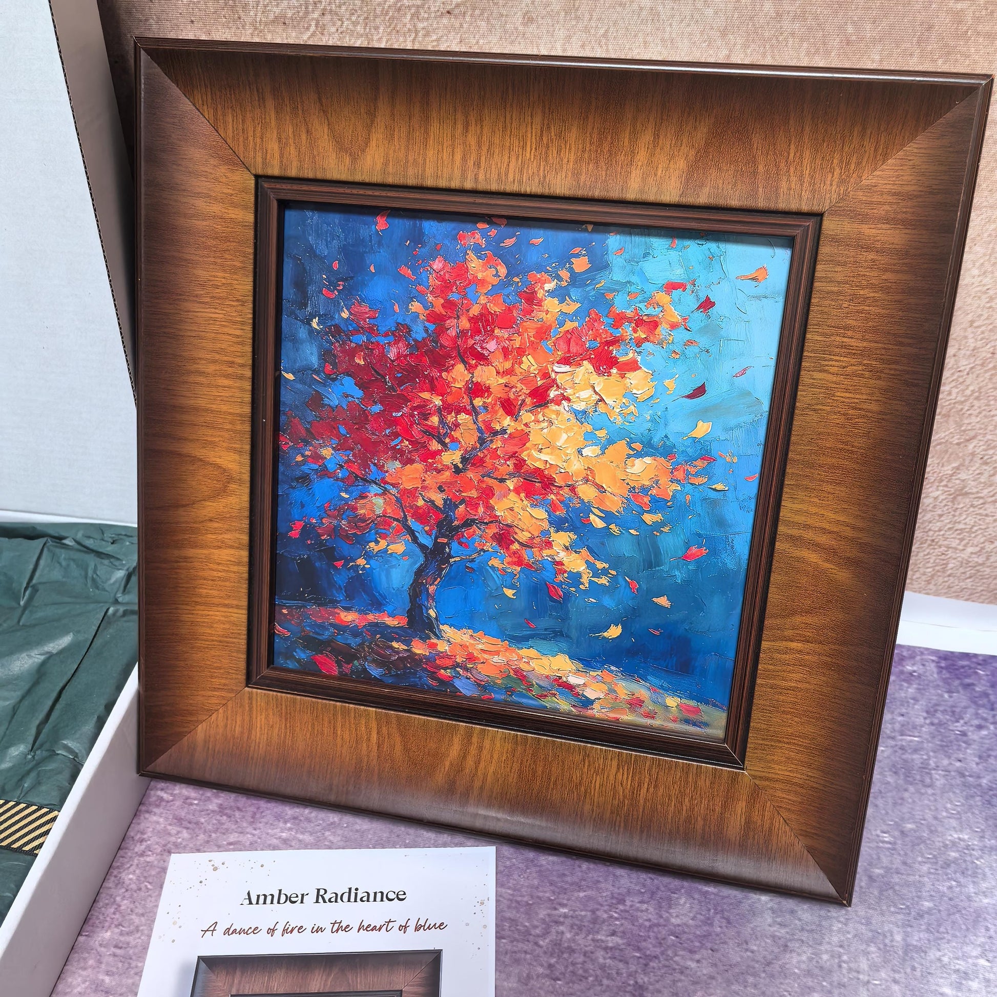 A front-facing view of the "Amber Radiance" framed print, showcasing a vibrant, impasto-style painting of a red and orange tree against a deep blue background, set in a wide, textured wood frame.