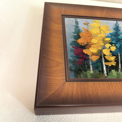 Close-up angled shot showing the wood grain and deep profile of the square frame surrounding a colorful impasto nature print.