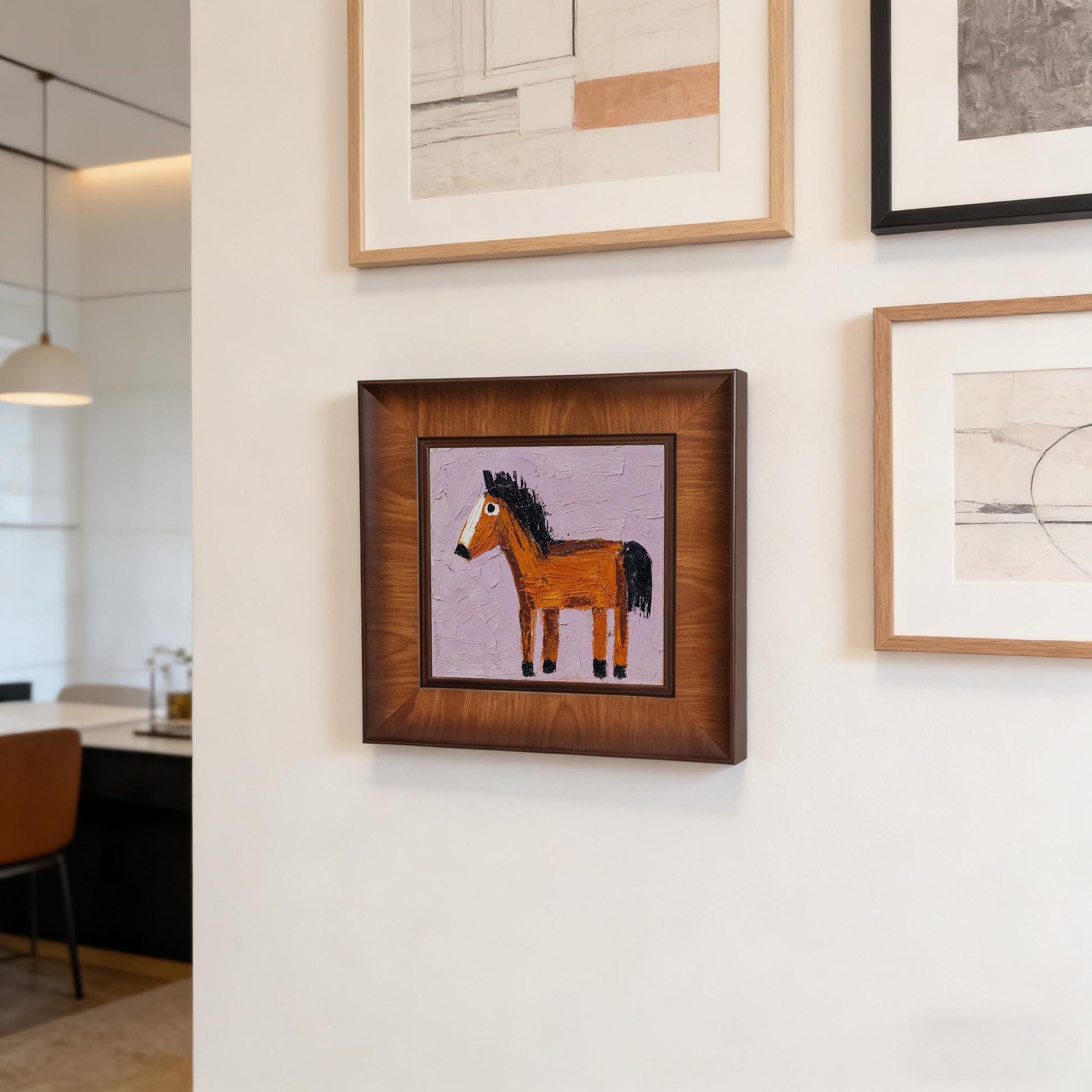 Framed horse oil painting featured in a gallery wall arrangement on a white wall, showcasing the dark wood frame among other art pieces.